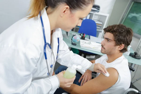 Young doctor prepares an injection to a patient — Stock Photo, Image