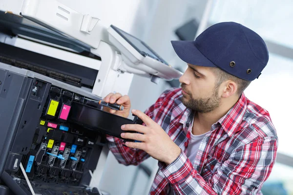 Jovem fixando impressora — Fotografia de Stock