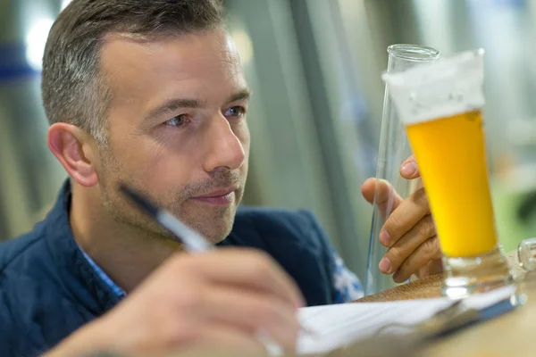 Travailleur de contrôle de la qualité inspectant le verre de bière — Photo