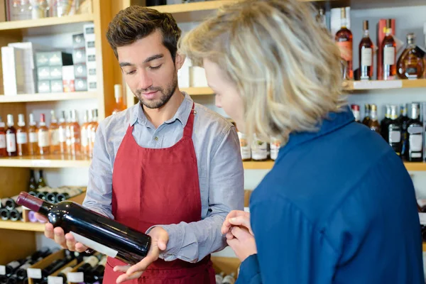 Wine merchant recommending bottle to customer — Stock Photo, Image
