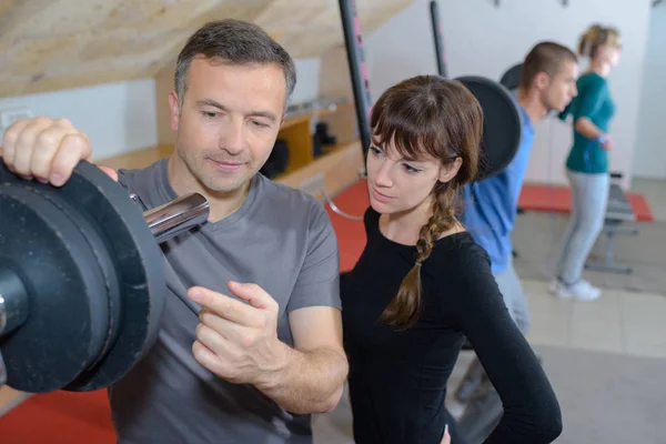 Treinador explicando como usar a máquina de treinamento em um ginásio — Fotografia de Stock