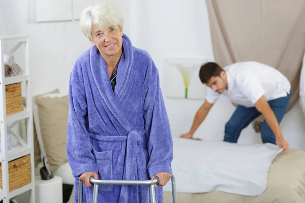 Äldre kvinna ambulates från sin säng med en walker — Stockfoto