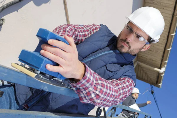 Tischler schleift bei Kunden zu Hause eine Planke — Stockfoto