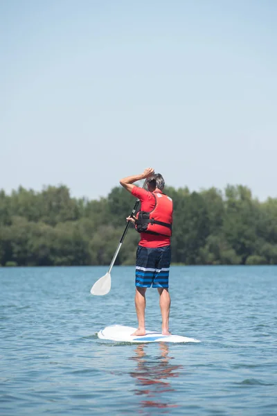 Homem desfrutando de um passeio no lago com paddleboard — Fotografia de Stock