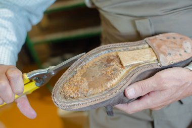 Shoe-repairer repairing a shoe sole clipart