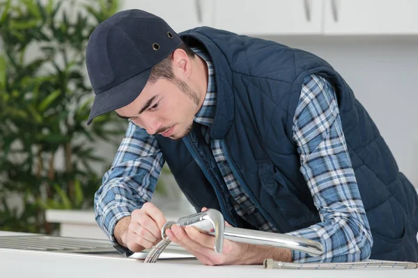 Jonge ambachtsman reparatie kraan in een keuken — Stockfoto