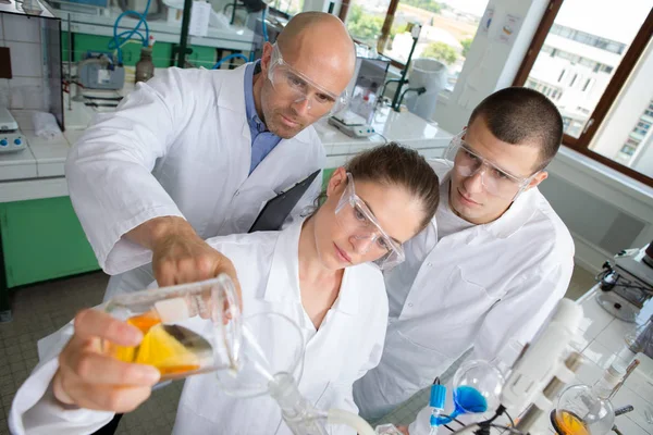 Učitel a studenti vědci kontrola trubky s kapalinou v laboratoři — Stock fotografie