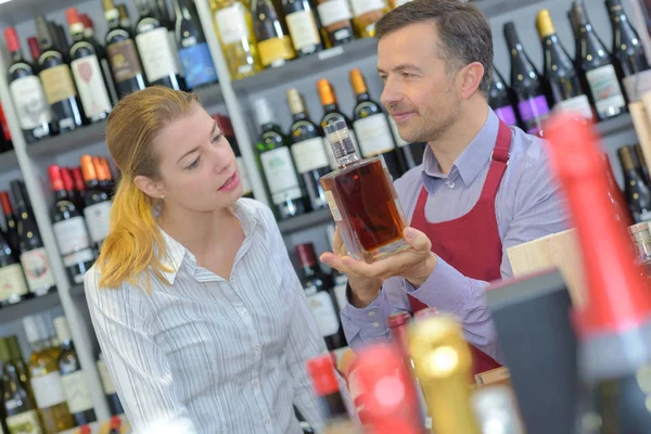 Liquor store worker showing bottle to customer