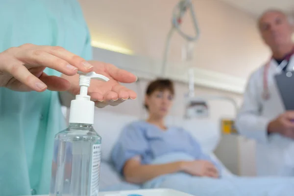 Enfermeira aplicando gel antibacteriano nas mãos — Fotografia de Stock