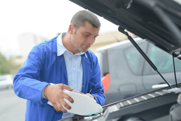 Mekanikern lägga till destillerat vatten i batteriet — Stockfoto