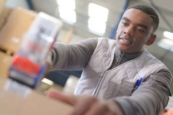 Warehouse worker taping parcel in distribution warehouse — Stock Photo, Image