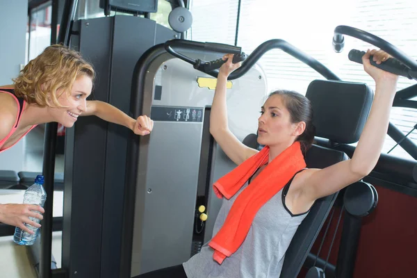 Entraîneur féminin aidant femme exercice dans la salle de gym — Photo