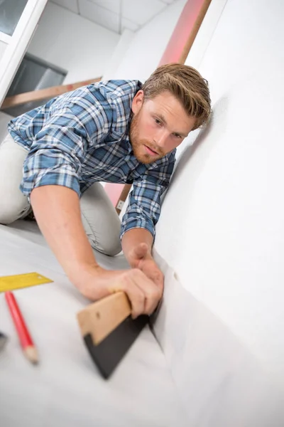 Young craftsman fitting a carpet — Stock Photo, Image
