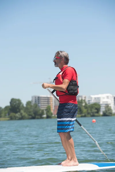 Uomo godendo di un giro sul lago con paddleboard — Foto Stock