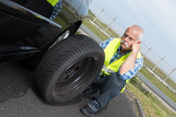 Mutloser Rentner kann Autoreifen nicht wechseln — Stockfoto