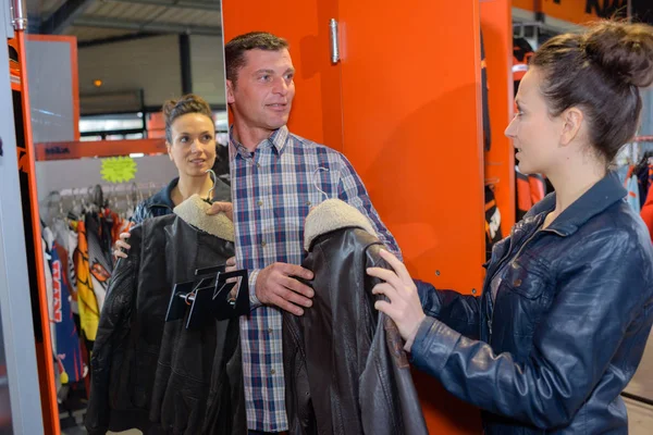 Uomo che passa giacca di pelle alla donna in negozio — Foto Stock