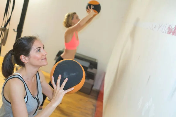 Две спортивные женщины делают упражнения с мячом для медицины — стоковое фото