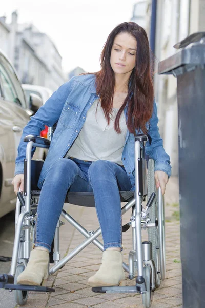 Jovem mulher em uma cadeira de rodas sozinha em uma cidade — Fotografia de Stock
