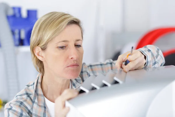 Blond klusjesvrouw schoonmaken vaststelling ventilatie systeem — Stockfoto