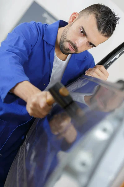 Mechanic fixing a car door with a hammer — Stock Photo, Image