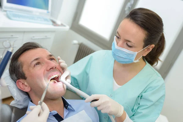 Жіночі стоматологи працюють на молодого пацієнта чоловічої статі — стокове фото