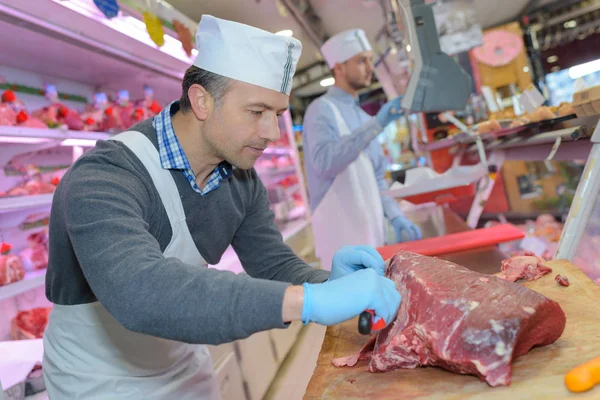 Carnicero enseñando a un joven a vender carne — Foto de Stock