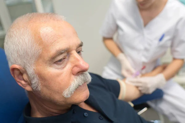 Sjuksköterska gör blodprov för senior man med diabetes — Stockfoto