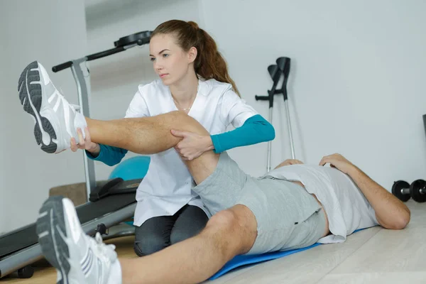 Θηλυκό physio θεραπευτής εργάζεται σε άνδρες ασθενείς στα πόδια — Φωτογραφία Αρχείου