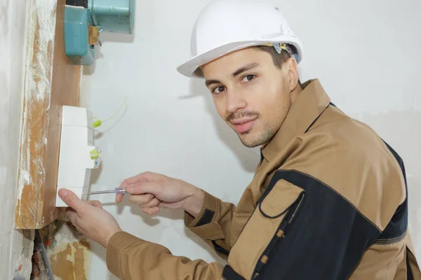 Jovem engenheiro construtor eletricista instalando uma caixa de fusíveis — Fotografia de Stock