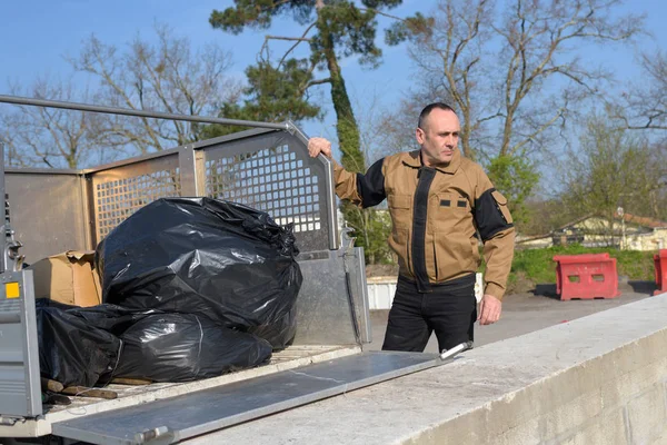 Szczęśliwy człowiek pracy, stojąc w pobliżu pojemnik na śmieci na ulicy — Zdjęcie stockowe