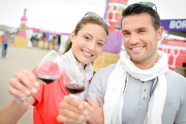 Couple toasting with red wine at wine event clipart