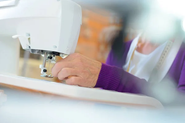 Крупный план женских рук с помощью швейной машинки — стоковое фото