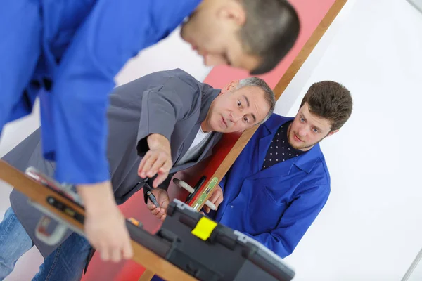 Homens jovens aprendendo a consertar a porta com chave de fenda — Fotografia de Stock