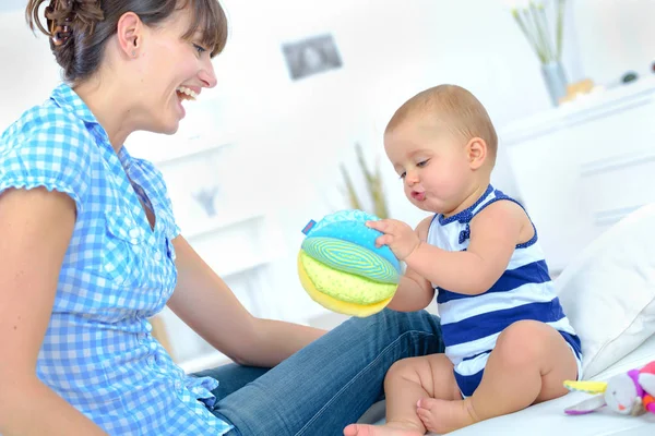 Ziemlich glückliche Mutter spielt mit ihrem süßen kleinen Kleinkind — Stockfoto