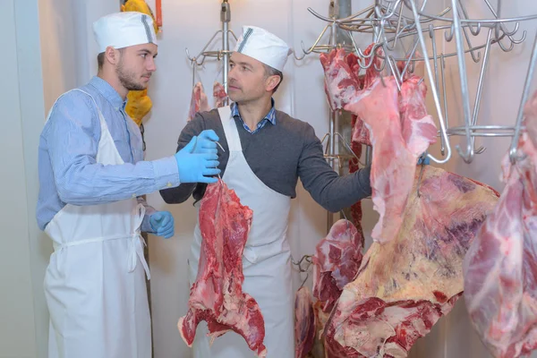 Açougueiros pendurado carne em ganchos — Fotografia de Stock