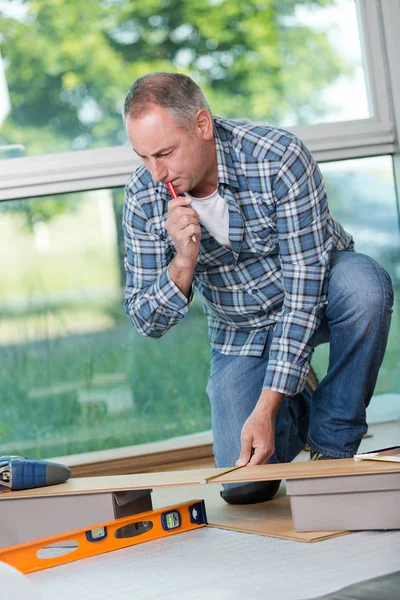 Homem que estabelece piso laminado em uma casa — Fotografia de Stock