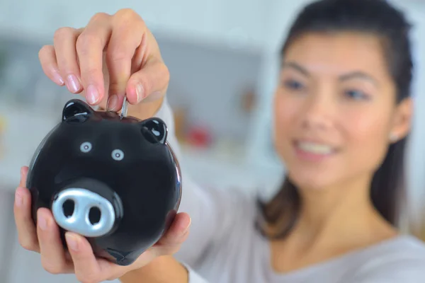 Close up of female hand putting coin into piggy bank — Stock Photo, Image