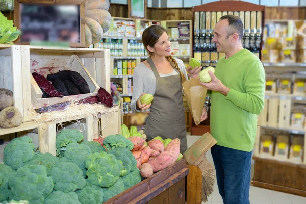 Cliente hablando con asistente de tienda mientras compra verduras —  Fotos de Stock