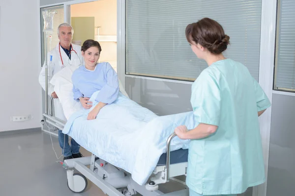 Personal médico moviendo al paciente a través del pasillo del hospital —  Fotos de Stock