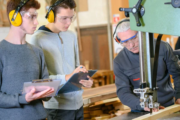 Timmerman met leerlingen in werkplaats — Stockfoto