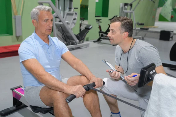 Älterer Mann zieht etwas Muskelkraft in der Turnhalle — Stockfoto