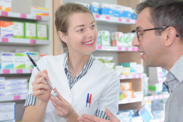 Farmacêutica feminina aconselhando cliente sobre o uso de drogas na farmácia moderna — Fotografia de Stock