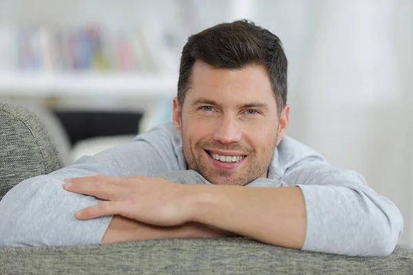 Joven guapo sentado en sofá — Foto de Stock