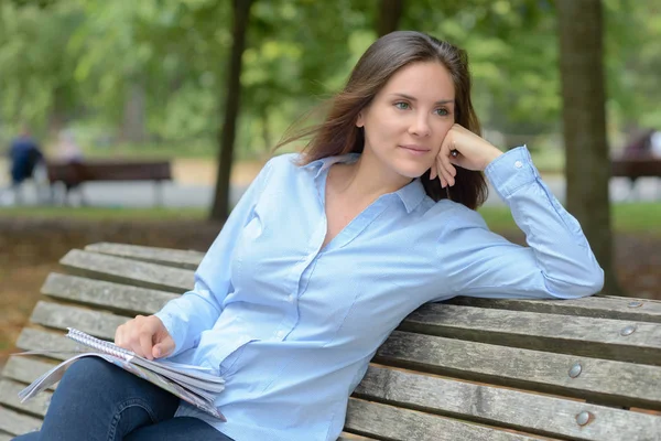 Писательница сидит на скамейке в парке — стоковое фото