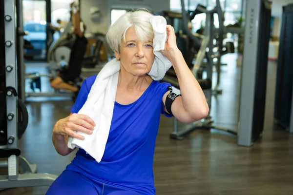 Senior oude vrouw zweet van haar voorhoofd afvegen — Stockfoto