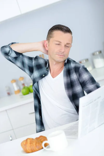 Geeuwen slaperig man koffie drinken en bezig met zijn notebook — Stockfoto