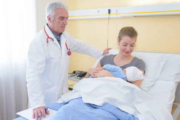 Médico vigilando a la madre con el bebé recién nacido en la cama del hospital —  Fotos de Stock