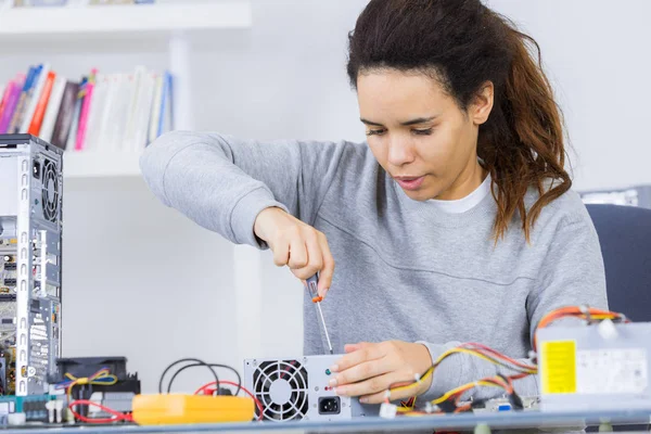 Happy woman fixing computer at desk at work — Stock Photo, Image