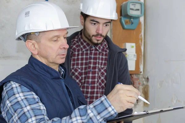 Two male contractors holding clipboard by electric meter — Stock Photo, Image