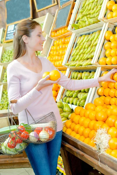 Woman picking up oranges — Stock Photo, Image